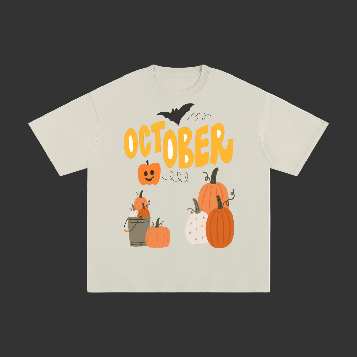 A light beige crewneck t-shirt featuring a Halloween graphic with the word 'OCTOBER' in yellow, pumpkins, a jack-o'-lantern, a bat, and a bucket of candy.