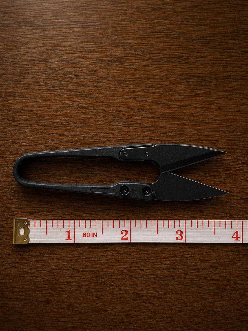 U-shape embroidery scissors displayed with measuring tape showing compact size for embroidery and sewing projects