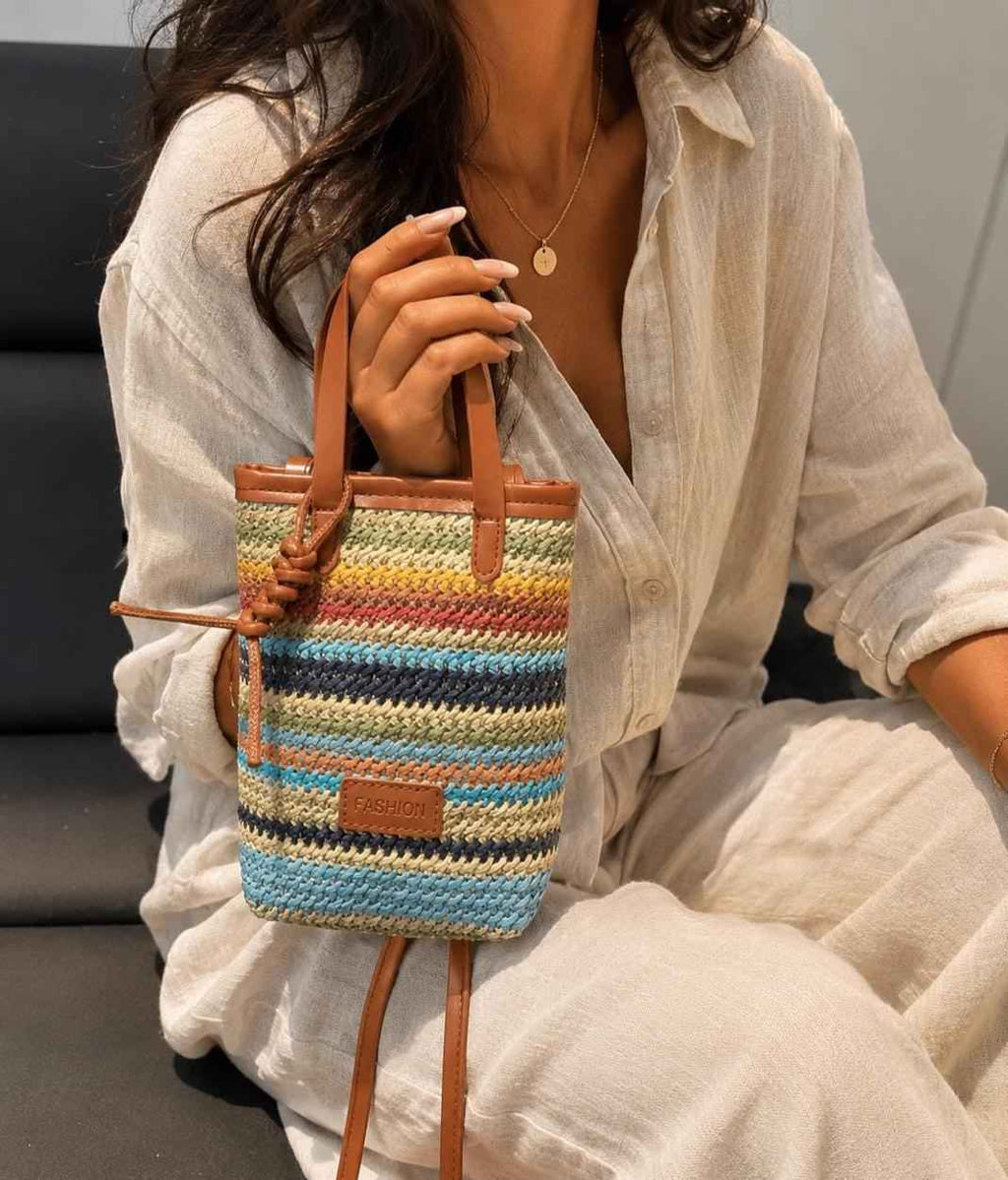 Woman holding colorful woven crossbody bag at outdoor market