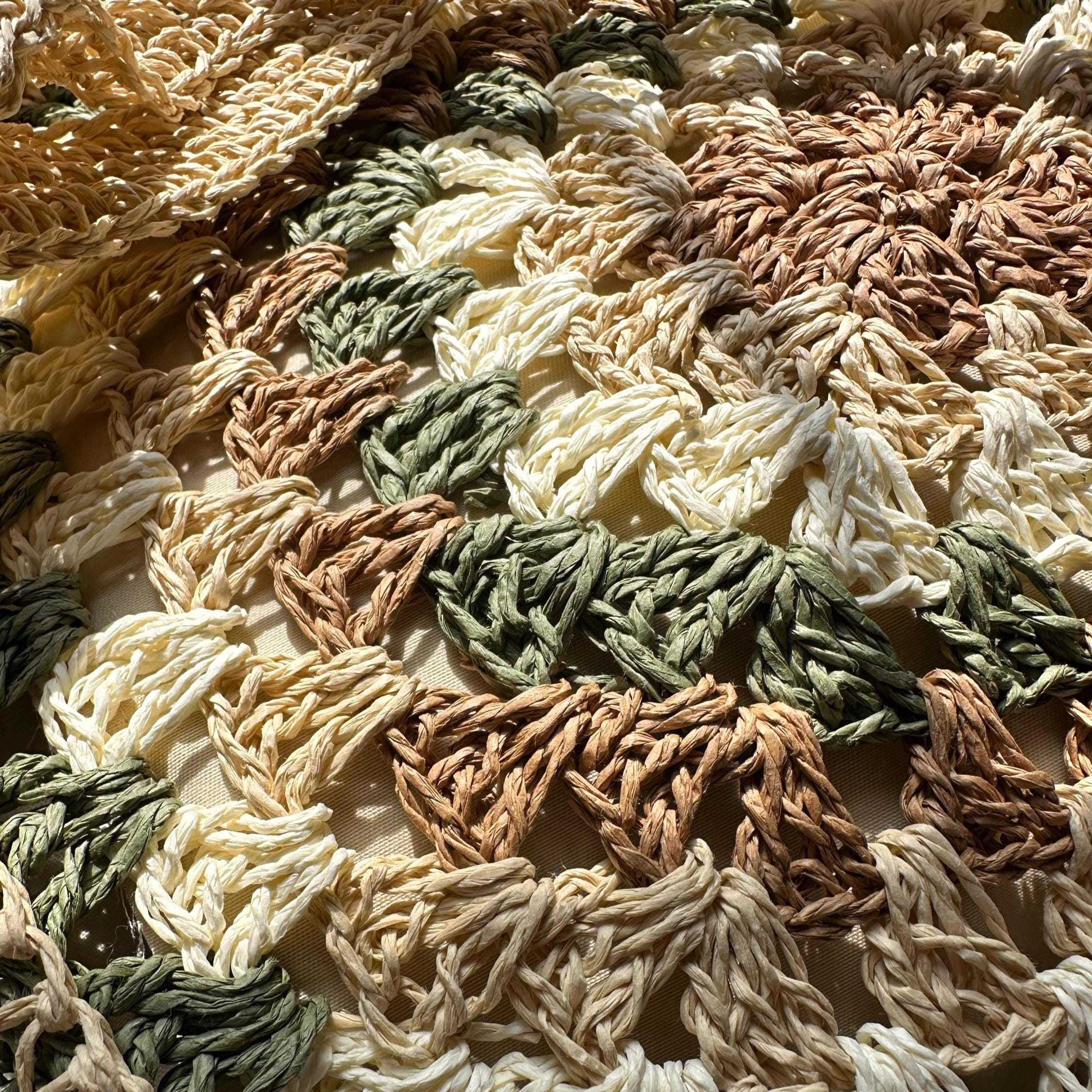 Close-up of hand-crocheted granny square pattern in neutral earth tones on boho tote bag