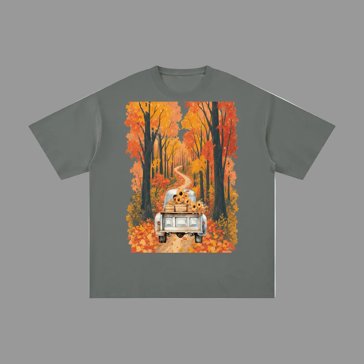 An olive green short-sleeve t-shirt with a large rectangular graphic print on the front. The graphic shows a white pickup truck driving down a winding road lined with orange and yellow autumn trees, with sunflowers sitting in the back of the truck.