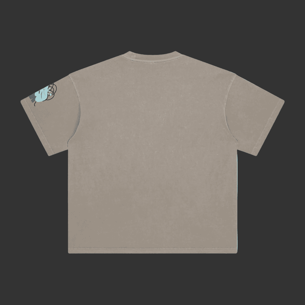 A light taupe gray short-sleeve t-shirt shown from the back, featuring a small graphic of a blue and black cartoon character on the left sleeve, set against a plain gray background.
