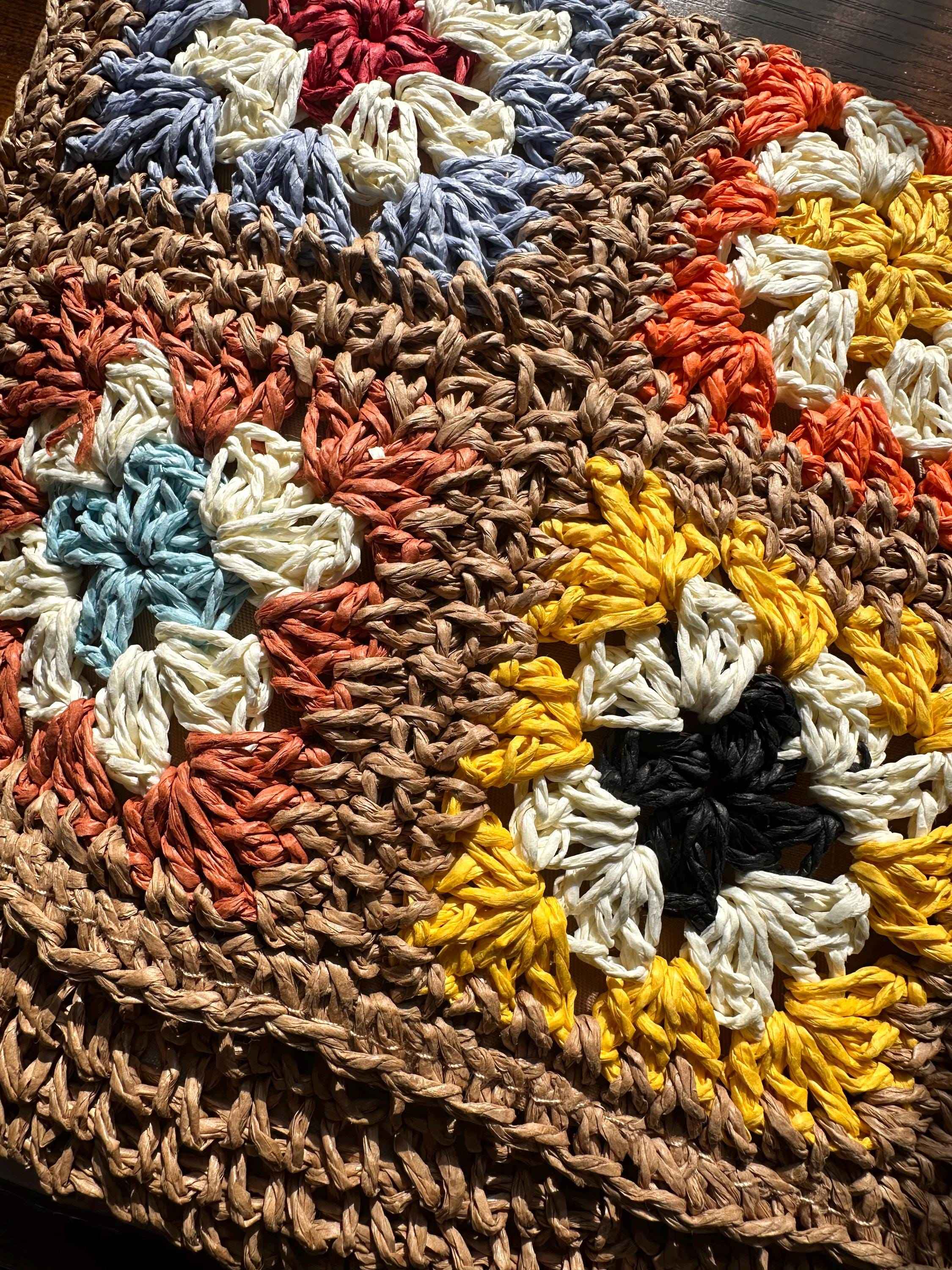 Close-up of handmade granny square crochet pattern with colorful floral motifs and textured yarn stitching