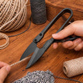 U-shape embroidery scissors cutting thread on a crafting table with yarn and sewing supplies