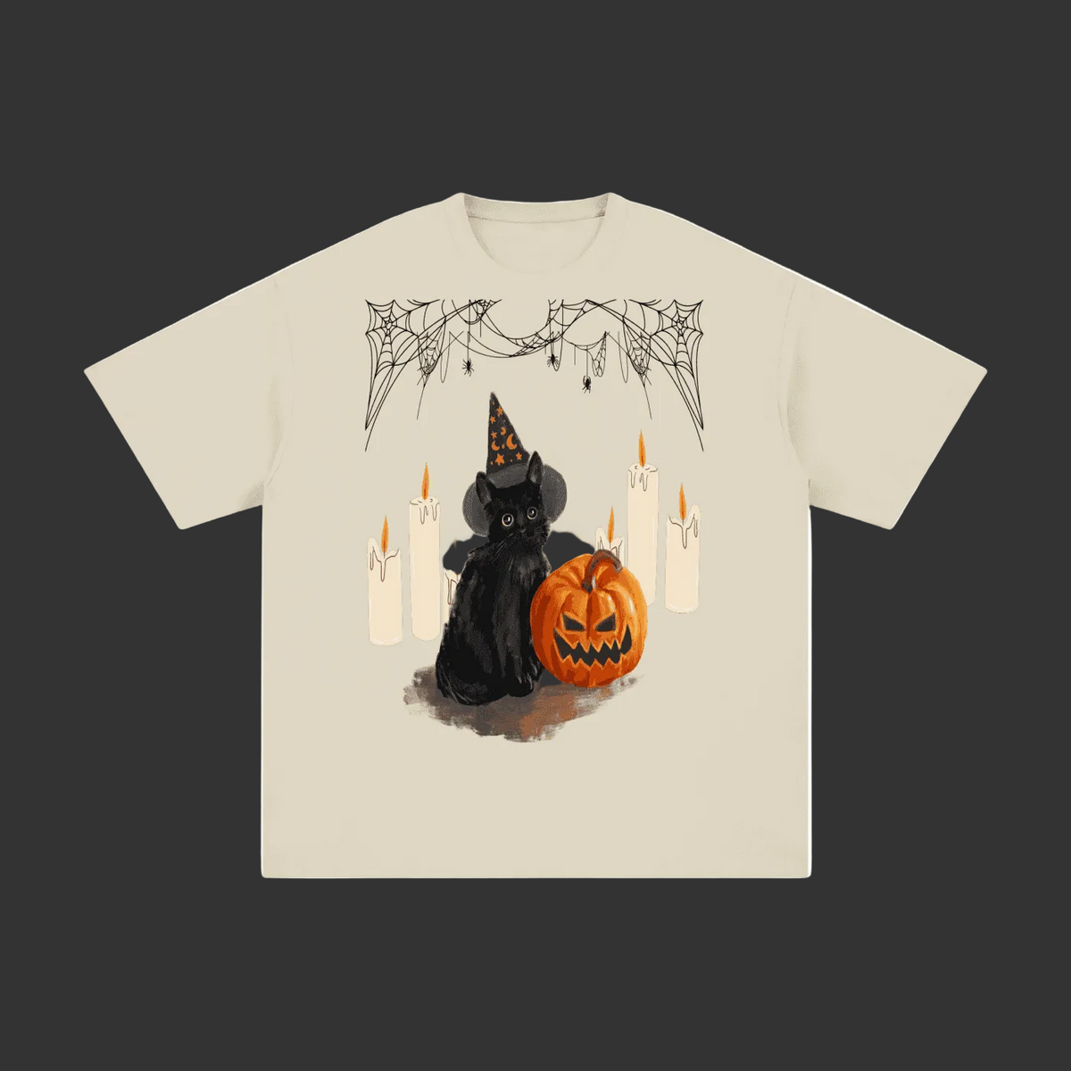 A beige short-sleeve t-shirt with a graphic print of a black cat in a witch hat next to a jack-o'-lantern pumpkin, surrounded by candles and spiderwebs, shown on a plain grey background.