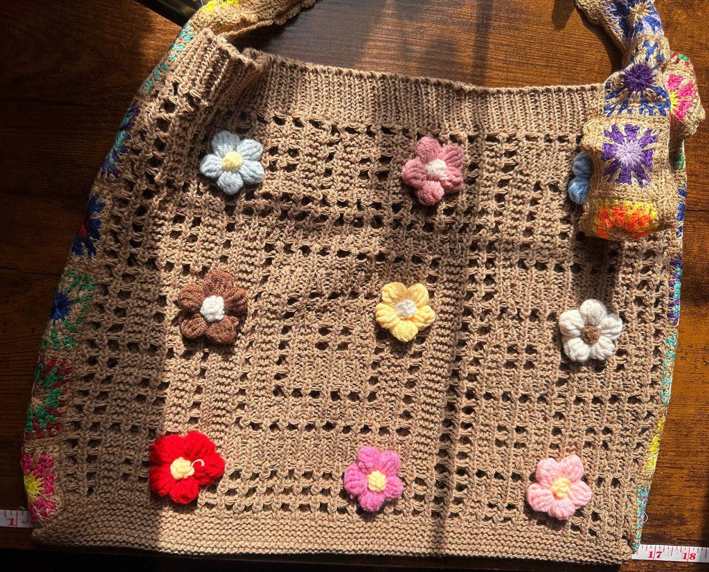 Handmade crochet tote bag with colorful floral appliqués, boho-inspired design, and spacious open-weave construction