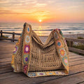 Boho crochet tote bag with granny square details on wooden deck at sunset