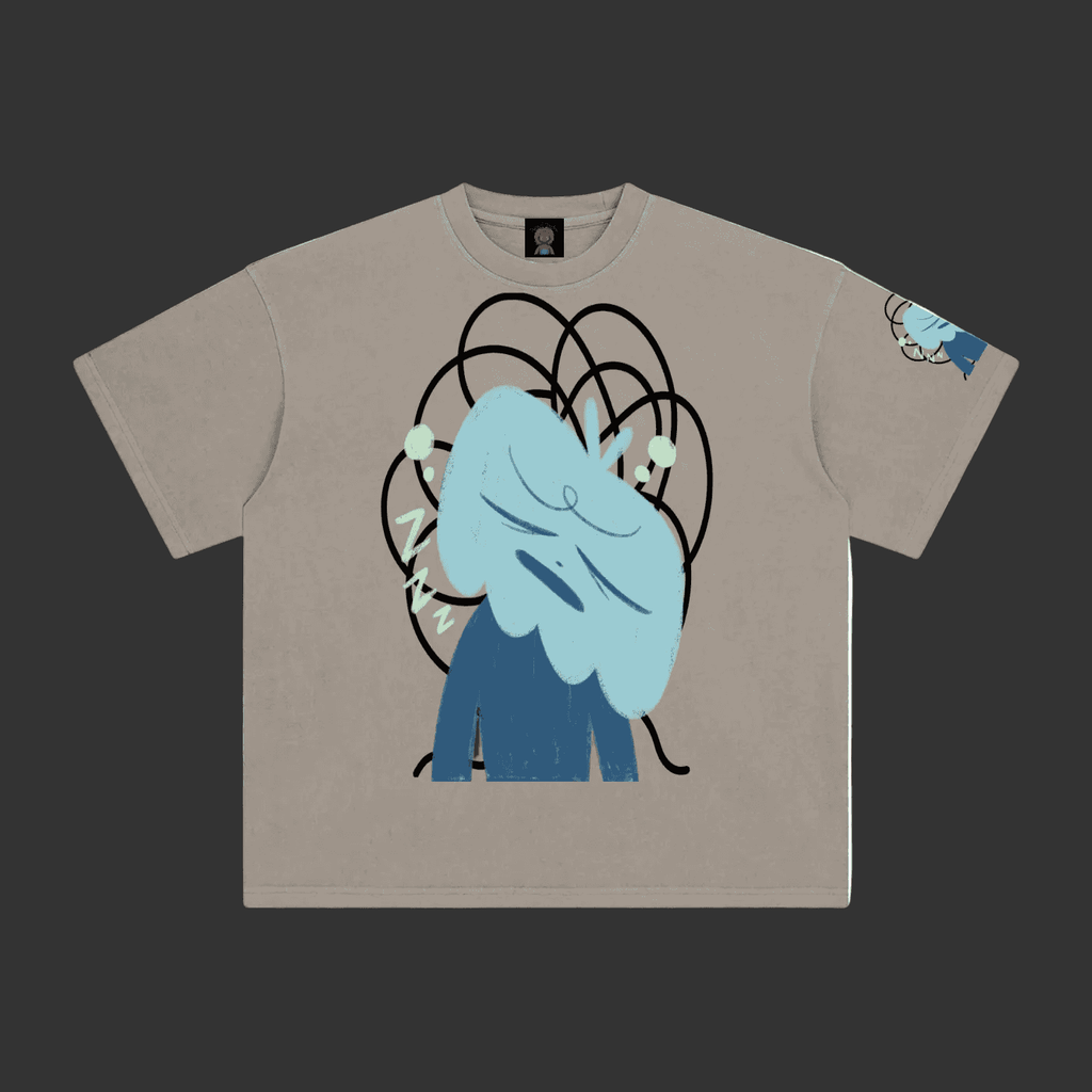 A light gray crewneck t-shirt featuring a graphic print of a blue cartoon character with messy hair and black scribbled lines, shown on a plain gray background.