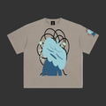 A light gray crewneck t-shirt featuring a graphic print of a blue cartoon character with messy hair and black scribbled lines, shown on a plain gray background.