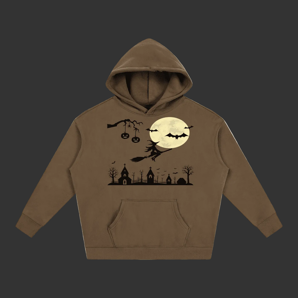 A brown pullover hoodie with a Halloween-themed graphic print on the front, featuring a witch riding a broomstick in front of a full moon, bats, pumpkins, and spooky church silhouettes, shown on a plain gray background.