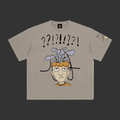 A light gray crewneck t-shirt featuring a cartoon graphic of a confused person with a lightbulb on their head and question marks above, shown on a plain gray background.