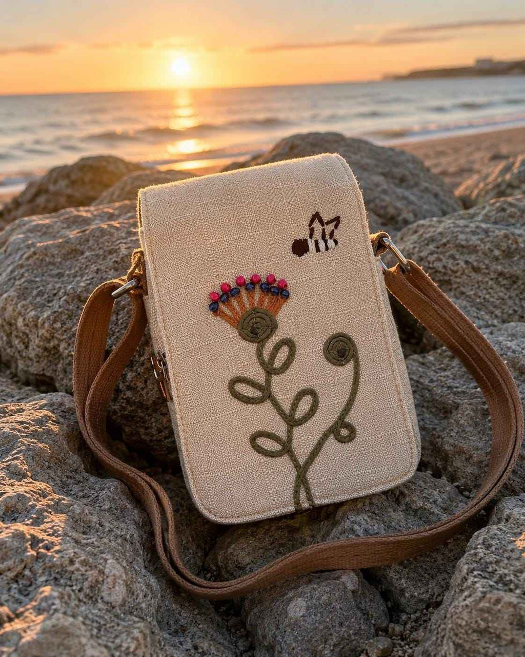 Boho floral crossbody phone pouch with embroidered flower design displayed on a sandy beach at sunset