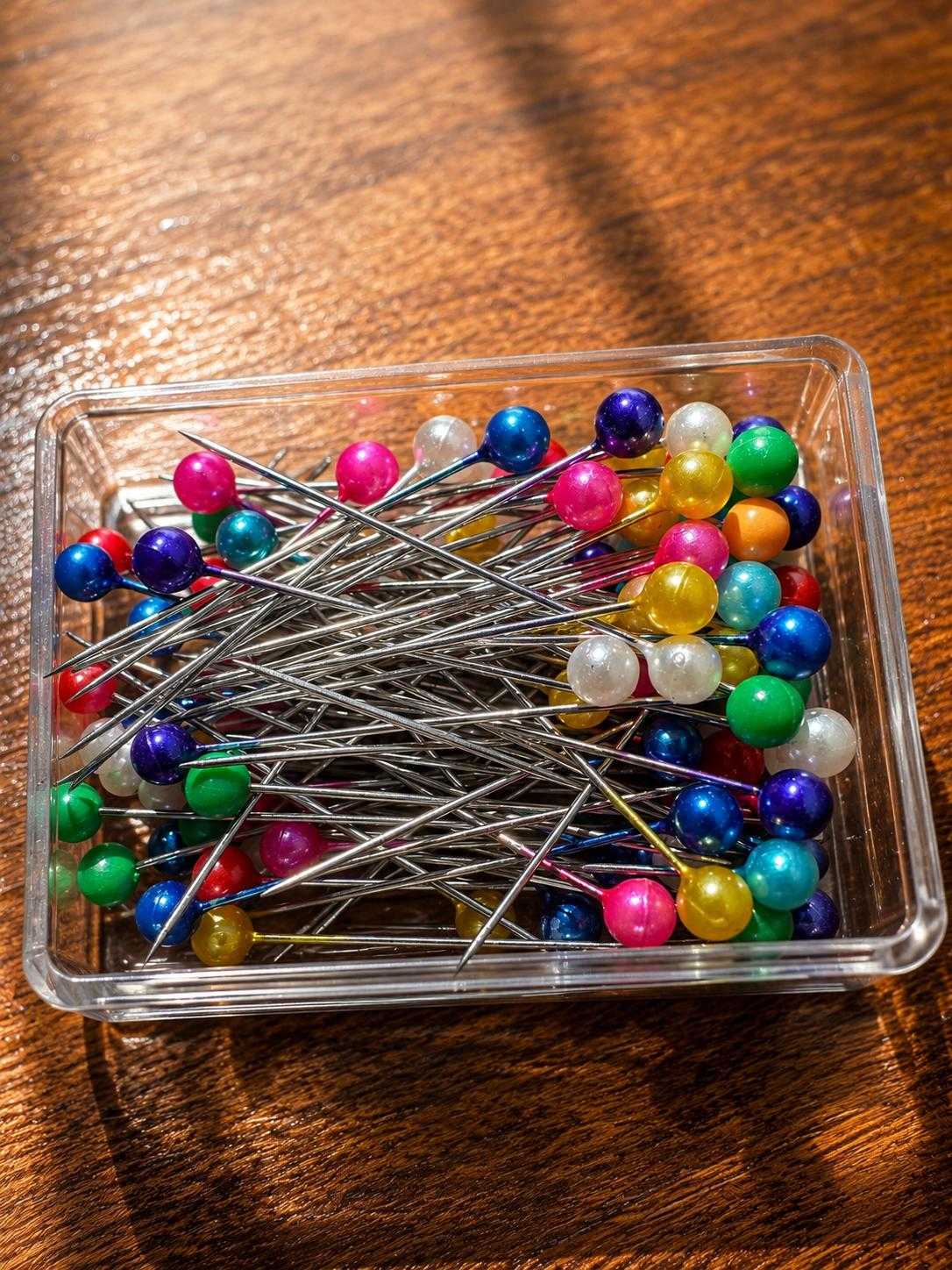 Colorful pearl head straight pins organized in a storage container for sewing, quilting, and dressmaking projects