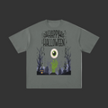A dark gray short-sleeve t-shirt with a Halloween graphic on the front. The graphic features the text 'Happy Halloween' in a distressed font, a large green and white eye, a green zombie hand, a pumpkin, and a spooky graveyard scene with bare trees.