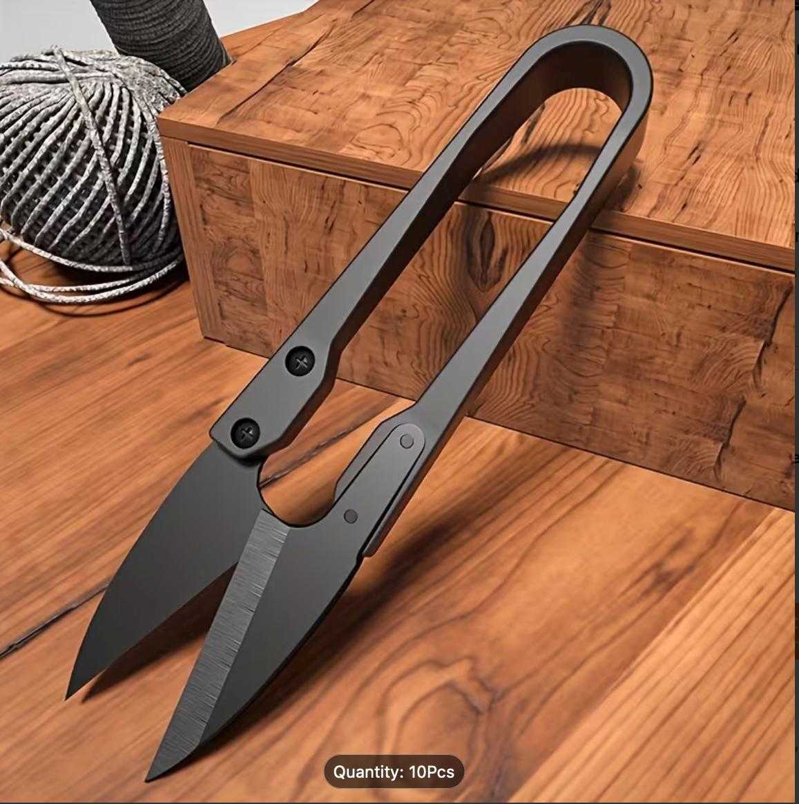 Large black U-shape thread snips on wooden surface with yarn for embroidery, sewing, and crafting