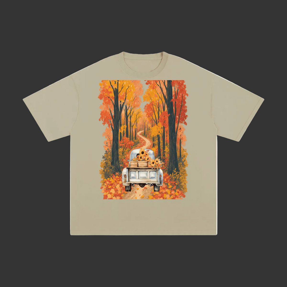 A beige crewneck t-shirt with a large rectangular graphic print on the front, showing a white pickup truck driving down a winding road lined with orange and red autumn trees with sunflowers in the back of the truck.