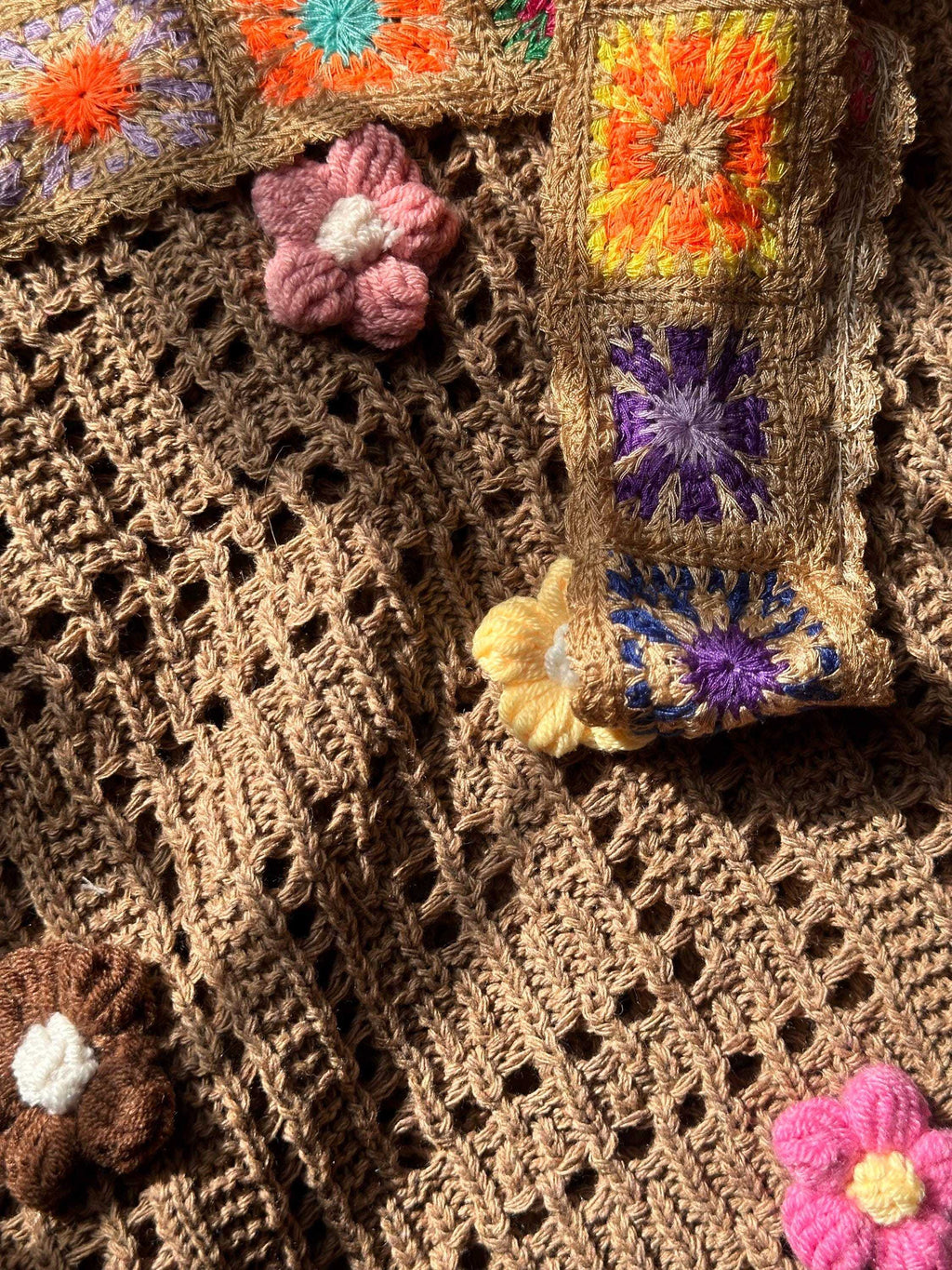 Close-up of boho crochet tote bag featuring textured open-weave stitching, colorful floral appliqués, and decorative shoulder strap