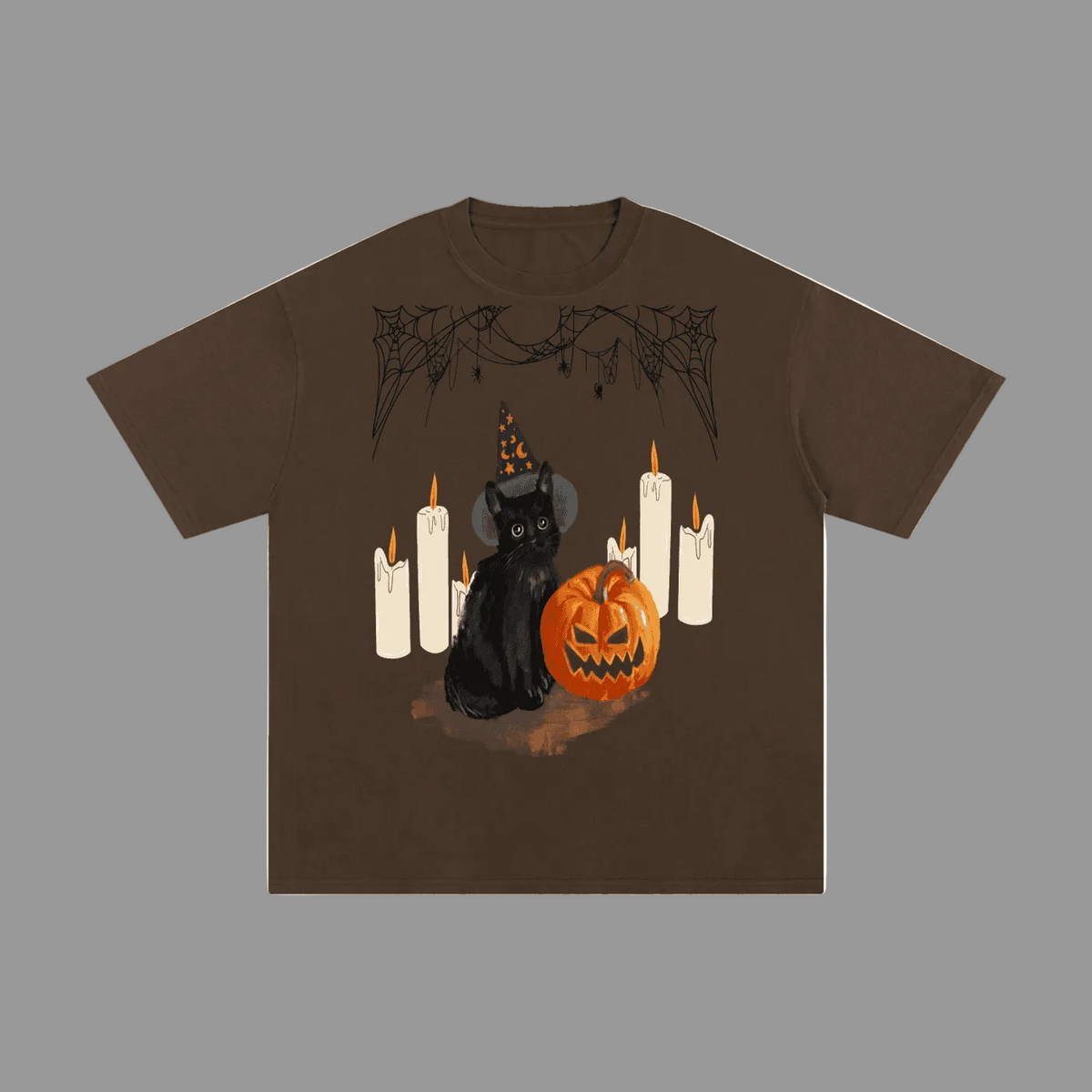 A brown short-sleeve t-shirt with a Halloween graphic featuring a black cat in a witch hat, a jack-o'-lantern pumpkin, and white candles, displayed on a solid grey background.