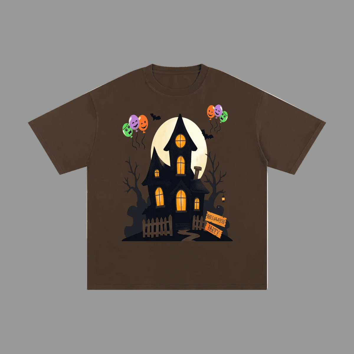 A brown short-sleeve crewneck t-shirt featuring a graphic of a spooky haunted house with glowing orange windows, jack-o'-lantern balloons, and a full moon on a plain gray background.