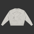 A light gray crewneck sweatshirt with a black line art graphic of a face, butterfly, and heart, accompanied by the text 'Be Kind To Your Mind' on a plain gray background.