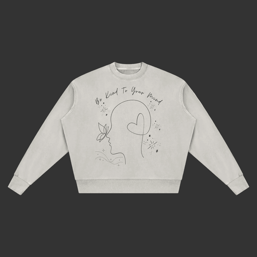 A light gray crewneck sweatshirt with a black line art graphic of a face, butterfly, and heart, accompanied by the text 'Be Kind To Your Mind' on a plain gray background.