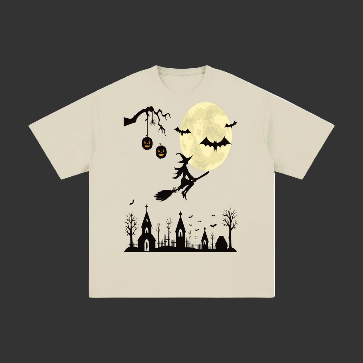 A light beige crewneck t-shirt featuring a black and yellow Halloween graphic print of a witch riding a broomstick in front of a full moon, with jack-o'-lanterns, bats, and a haunted house silhouette below.