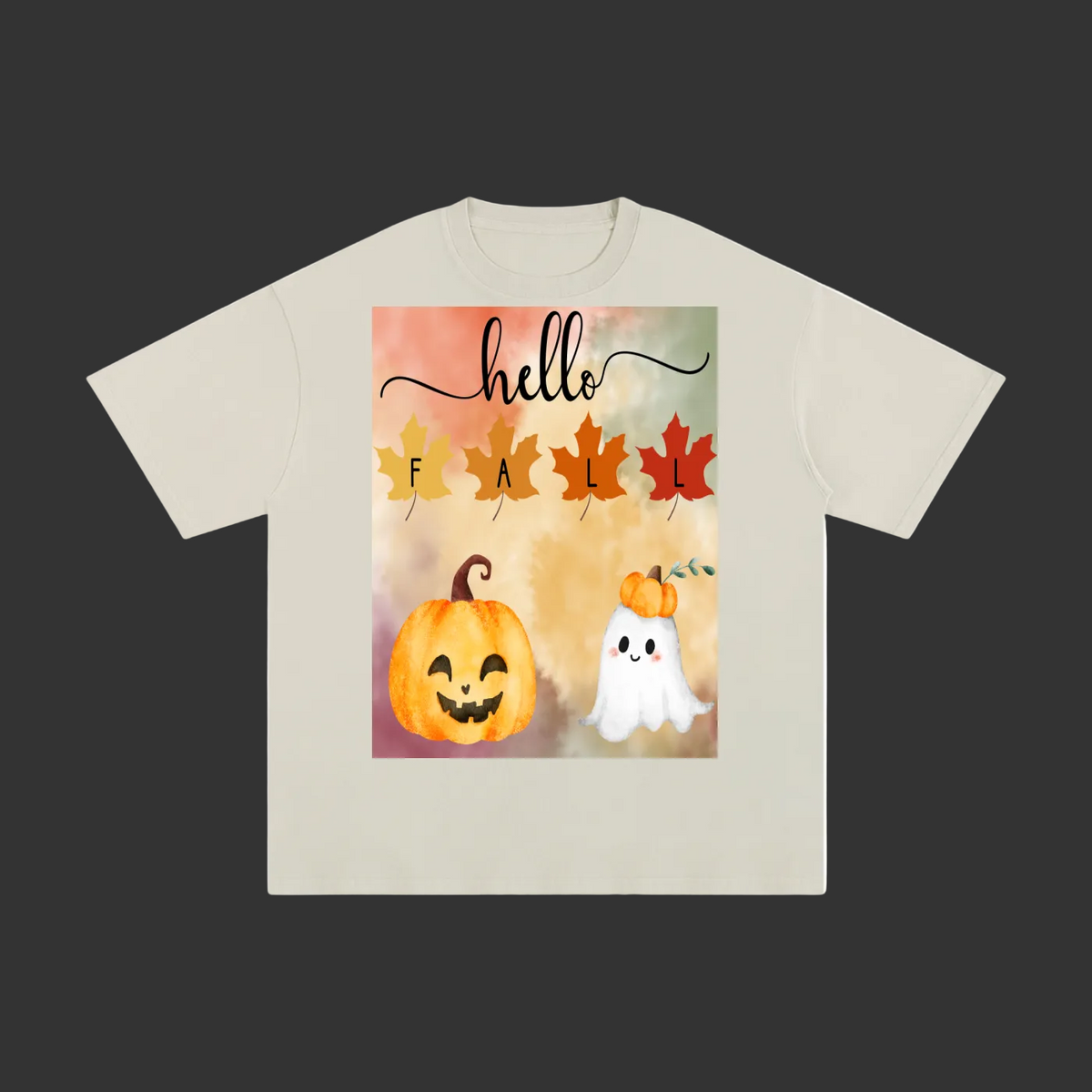 A light beige crewneck t-shirt featuring a colorful autumn-themed graphic print on the front with the text 'hello FALL' and illustrations of a jack-o'-lantern, a white ghost, and fall leaves.