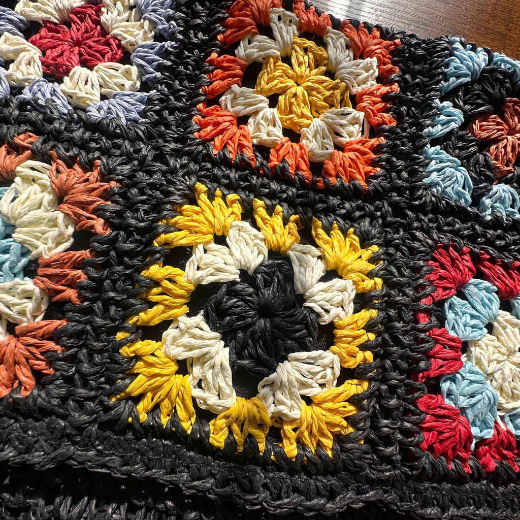 Close-up of colorful granny square crochet pattern with detailed floral stitching and handmade craftsmanship