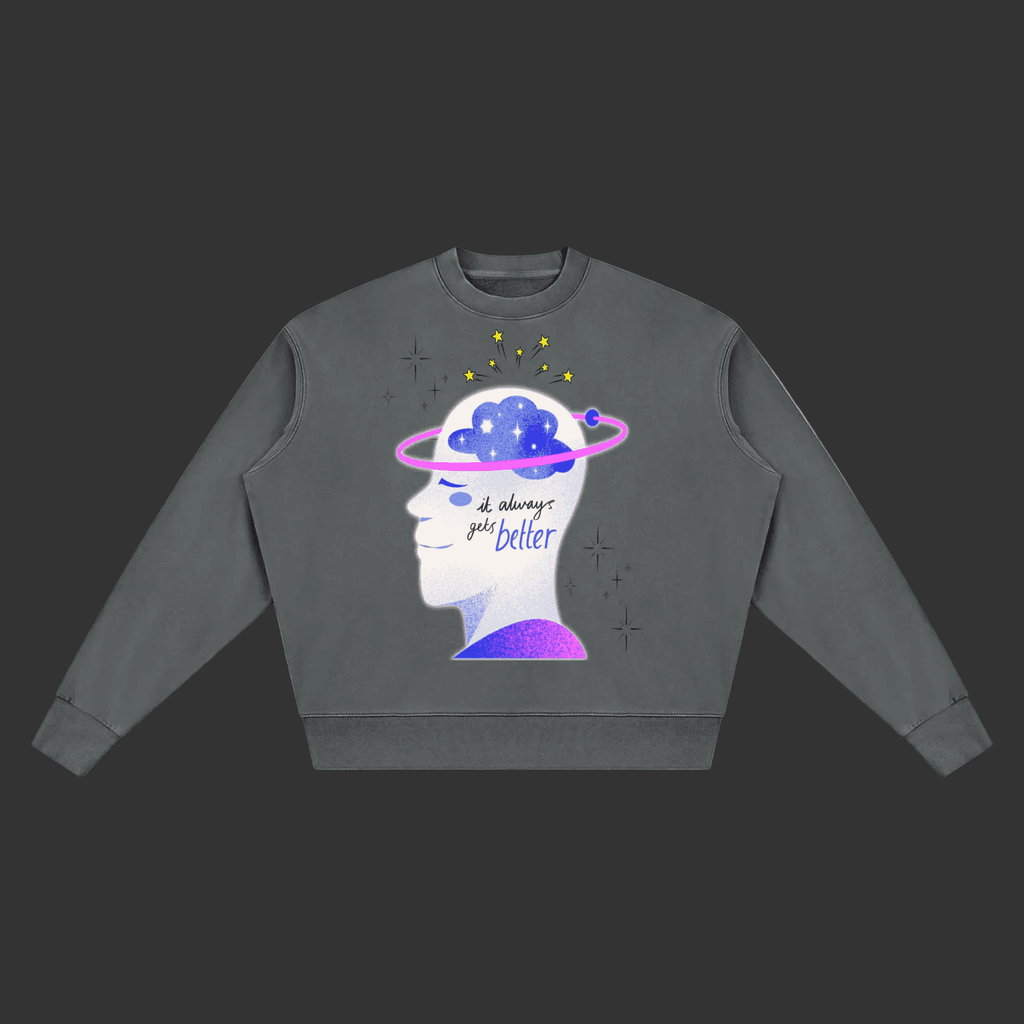A dark gray crewneck sweatshirt featuring a graphic of a human head profile with a Saturn-like ring and a blue cloud inside, accompanied by the text 'all things go better' in purple and black script.