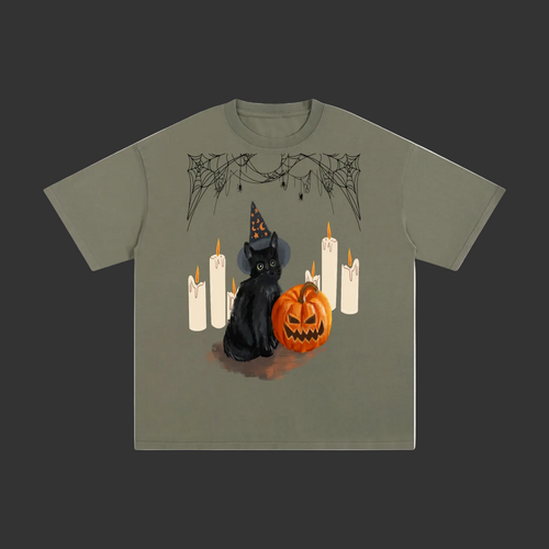 An olive green short-sleeve t-shirt featuring a Halloween graphic of a black cat in a witch hat next to a jack-o'-lantern pumpkin and white candles, displayed on a clean grey background