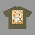 An olive green short-sleeve t-shirt with a central square graphic print of two cartoon white geese wearing orange boots and holding pumpkins, surrounded by autumn leaves on a warm beige background.