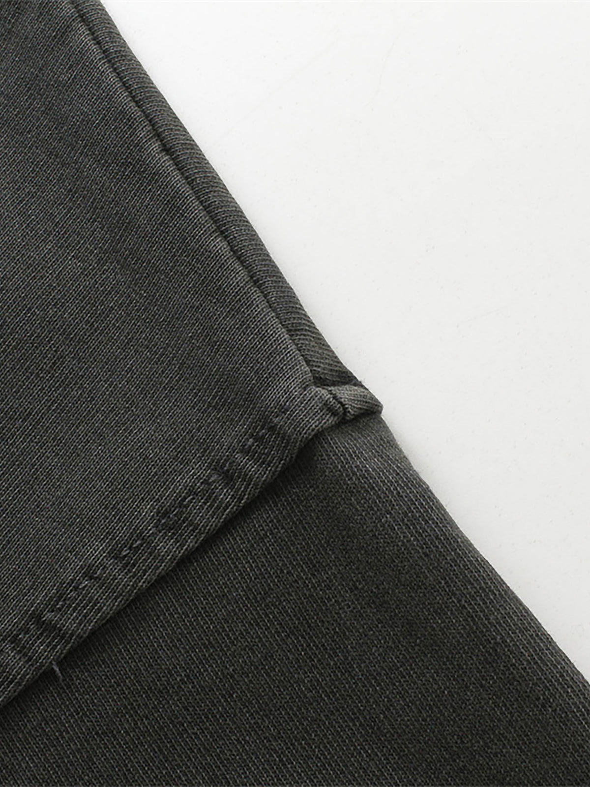 Close-up of dark gray pants with a white background