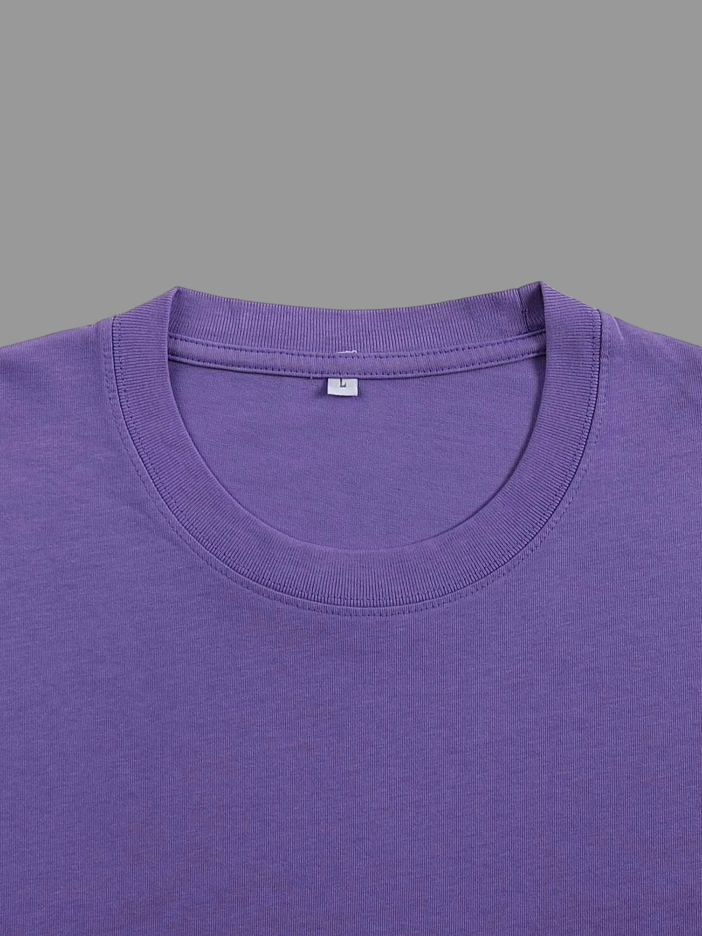 Close-up of a purple crewneck t-shirt showing the inner collar label with a size 'L' tag, on a solid gray background.