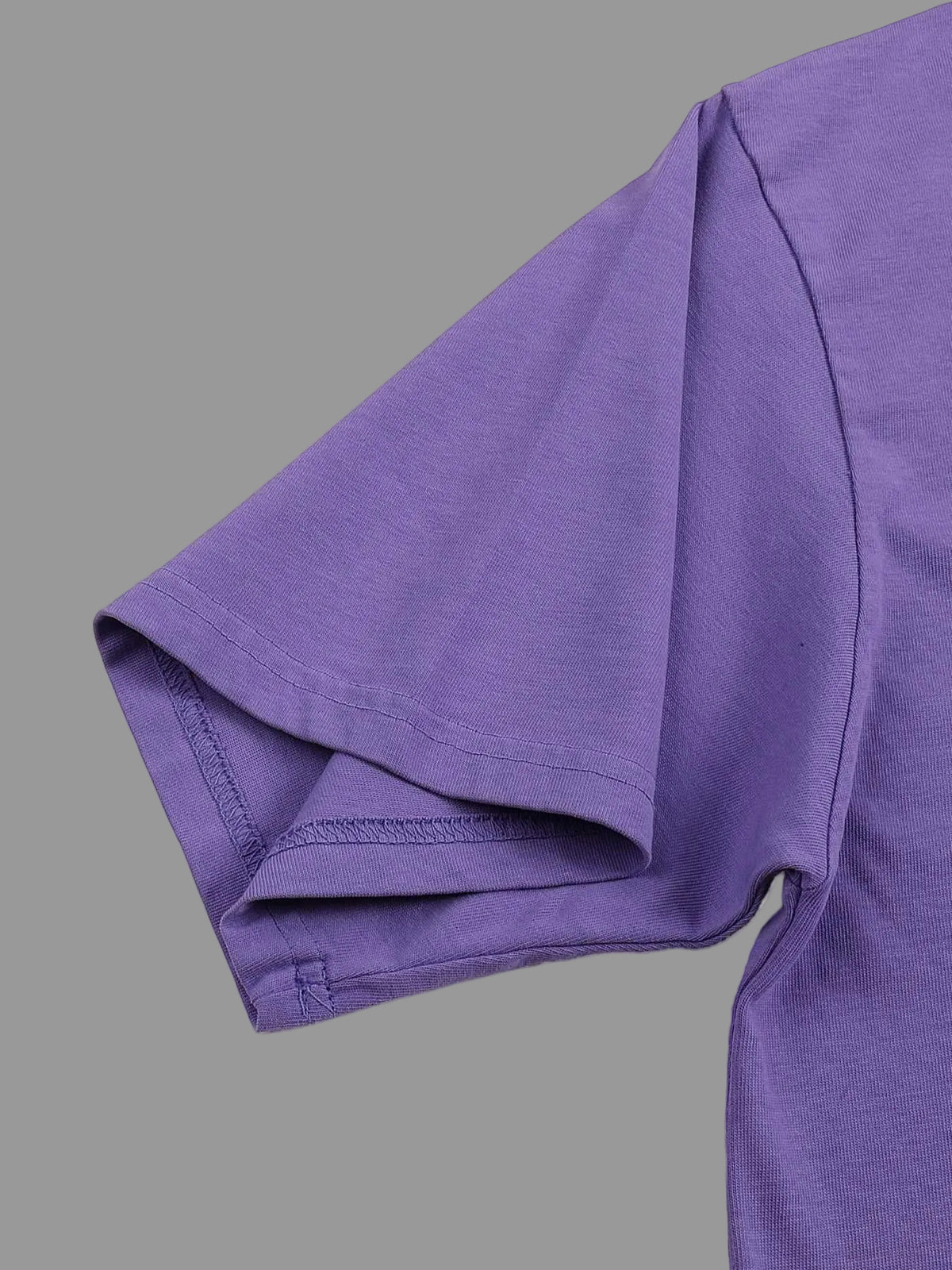 Close-up of a purple t-shirt sleeve on a gray background