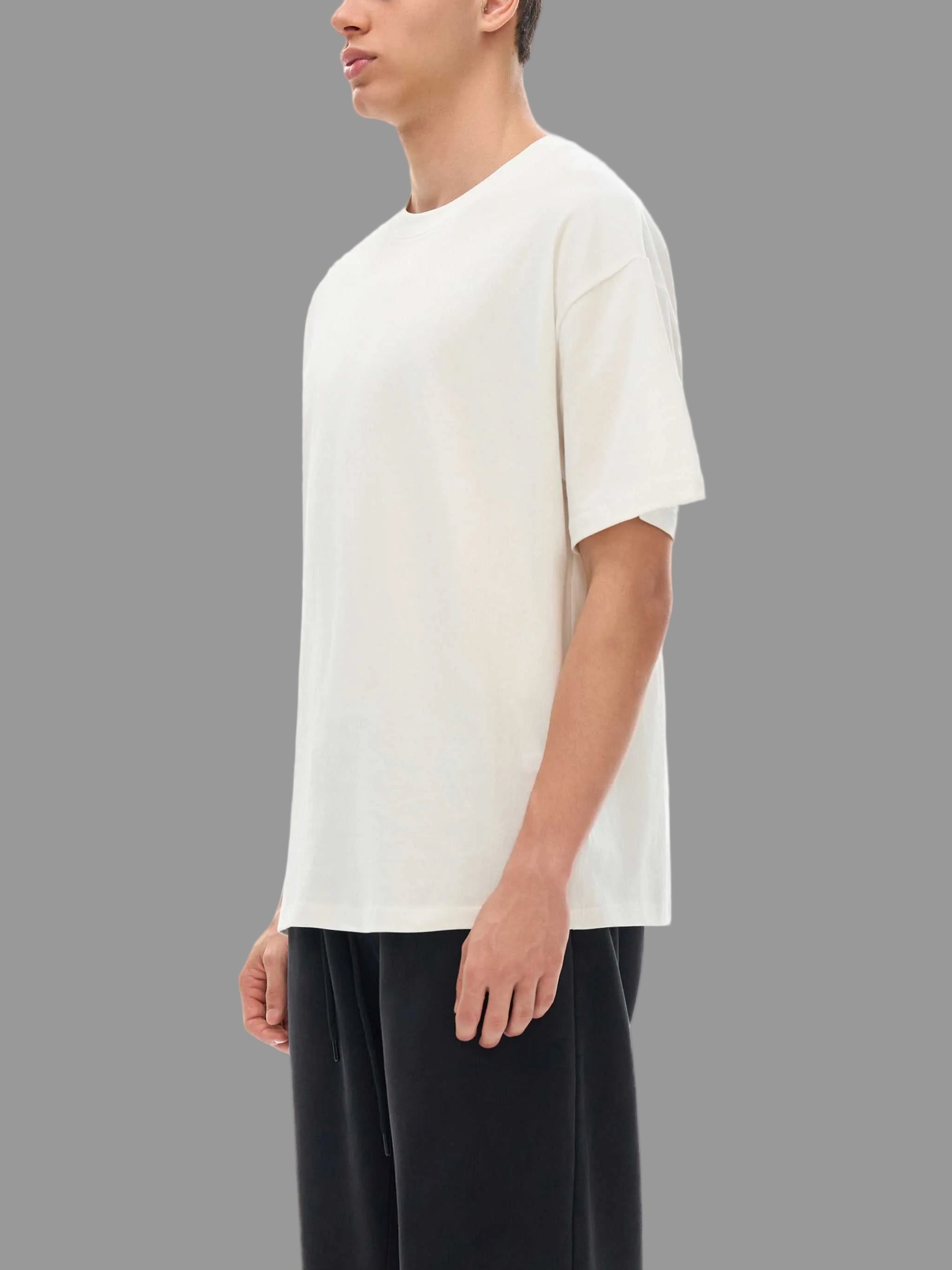Person wearing a white t-shirt and black pants on a gray background