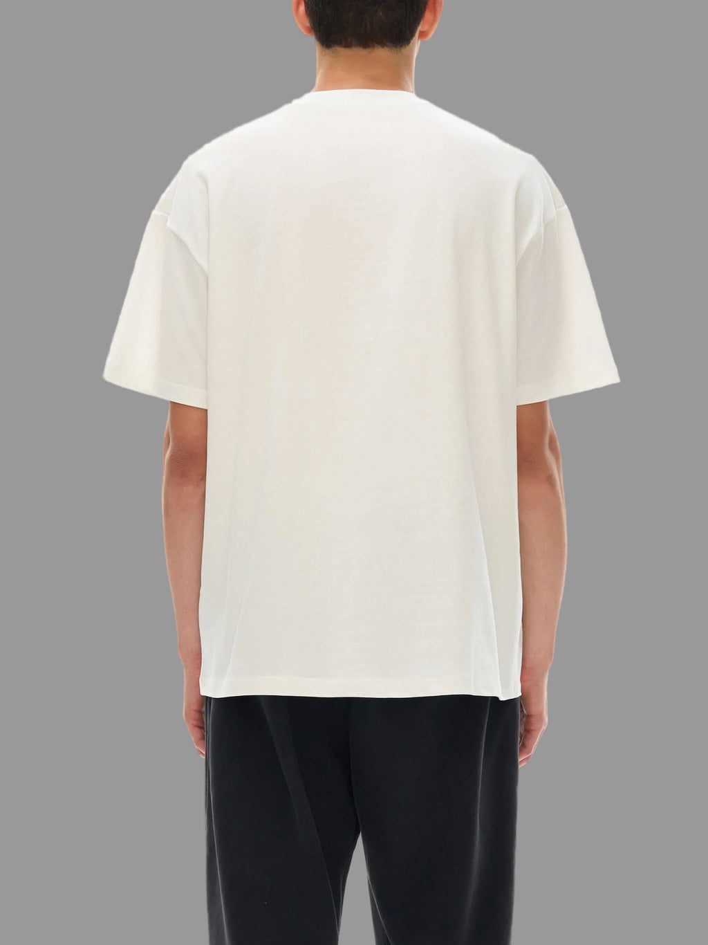 Person wearing a plain white t-shirt on a gray background