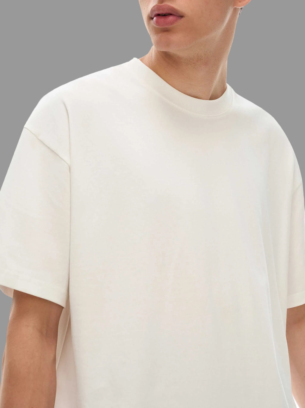 Person wearing a plain white t-shirt against a gray background