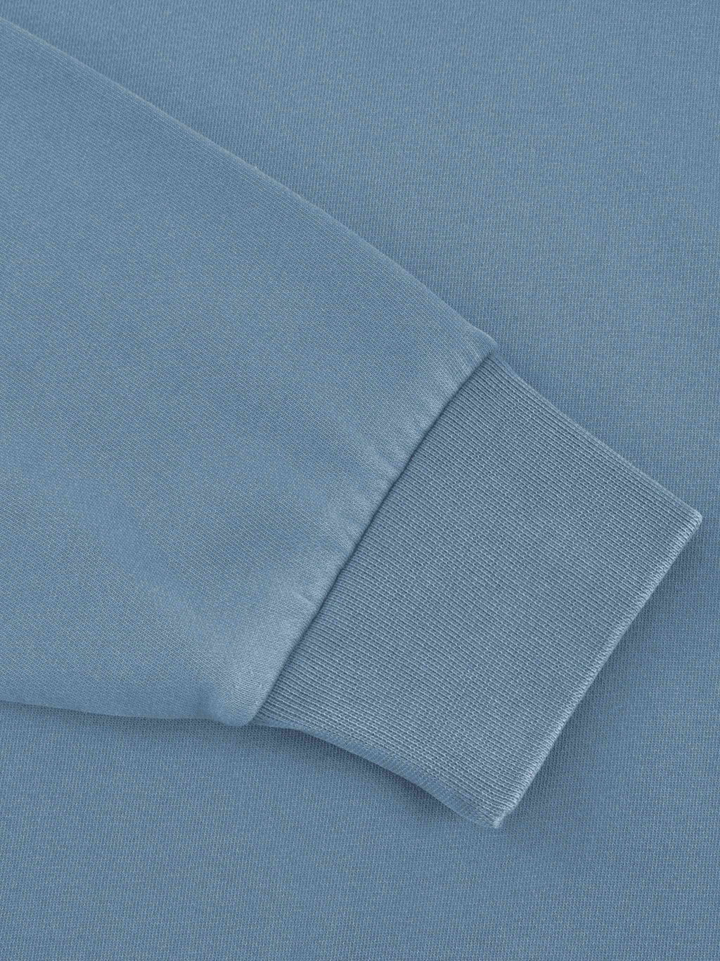 Close-up detail of a light blue sweatshirt sleeve showing the ribbed knit cuff.
