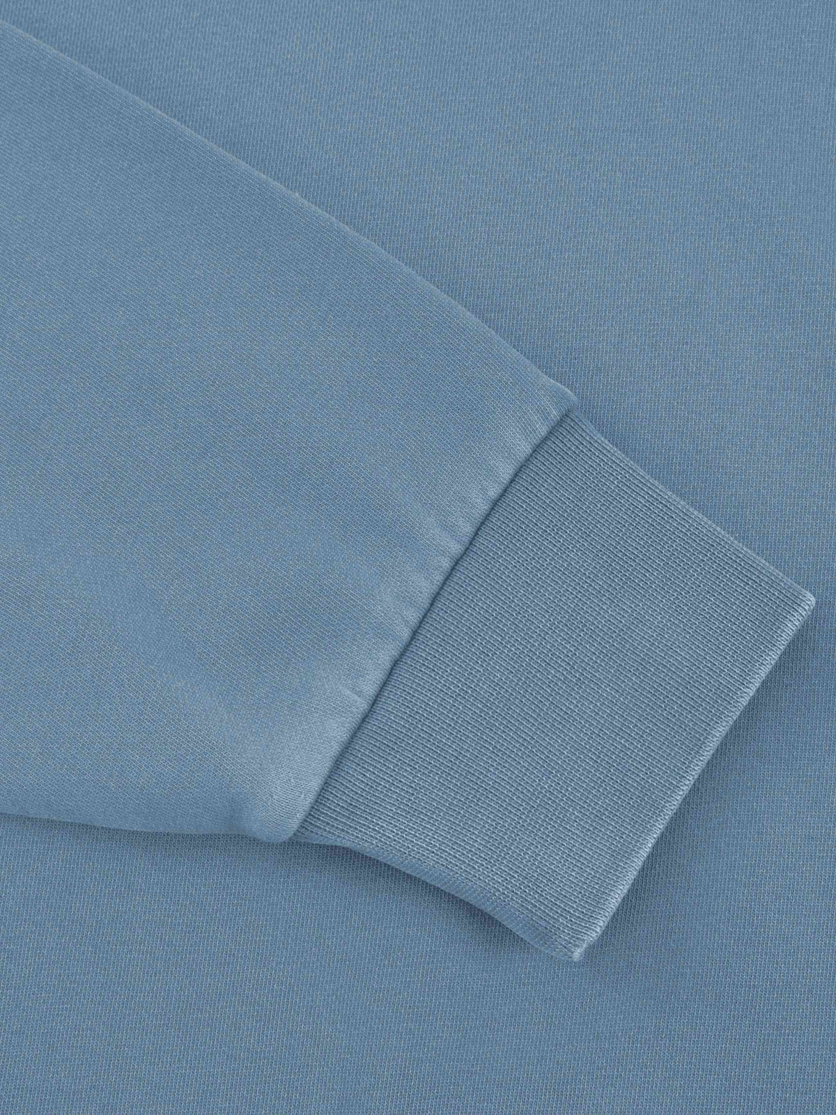 Close-up detail of a light blue sweatshirt sleeve showing the ribbed knit cuff.
