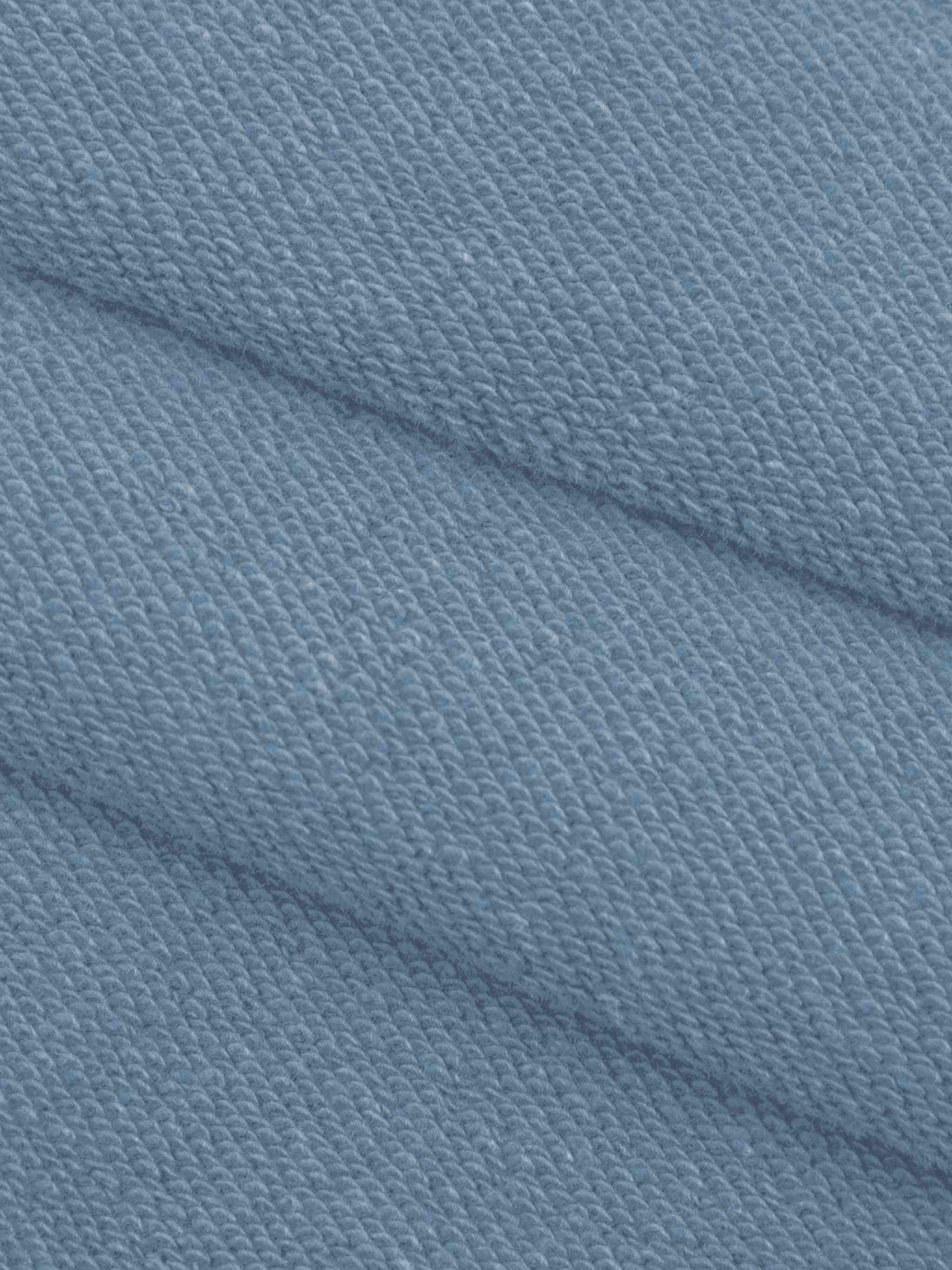 A close-up of textured knit fabric in a dusty light blue color, showing the weave pattern and soft folds.