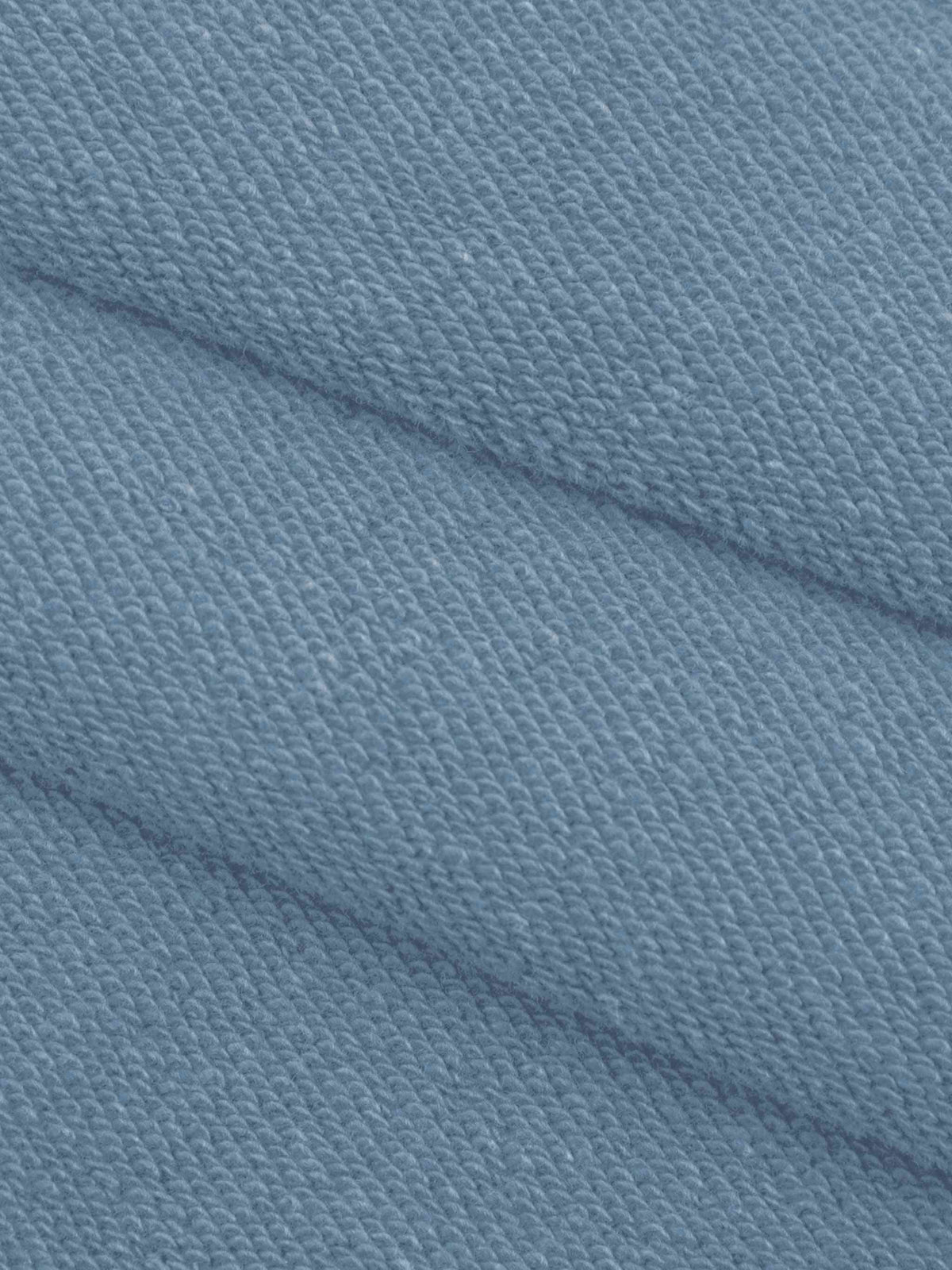 A close-up of textured knit fabric in a dusty light blue color, showing the weave pattern and soft folds.