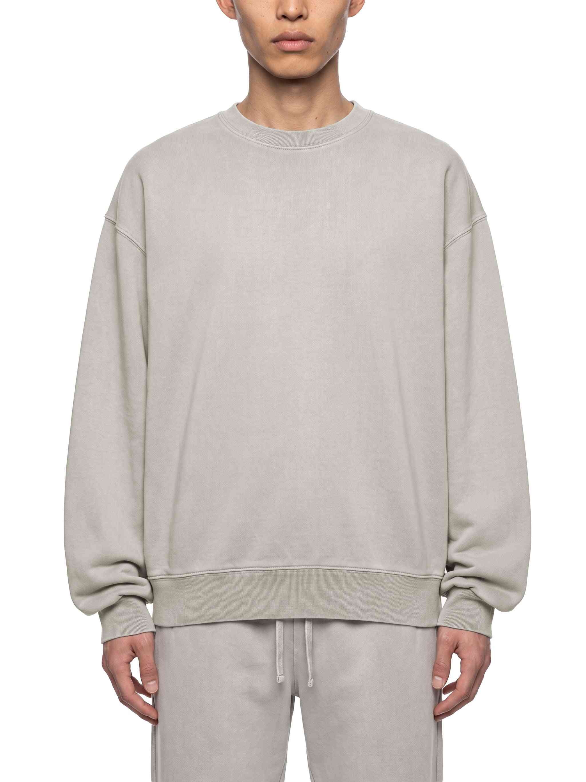 A model wearing a light gray crewneck sweatshirt and matching sweatpants against a plain white background.