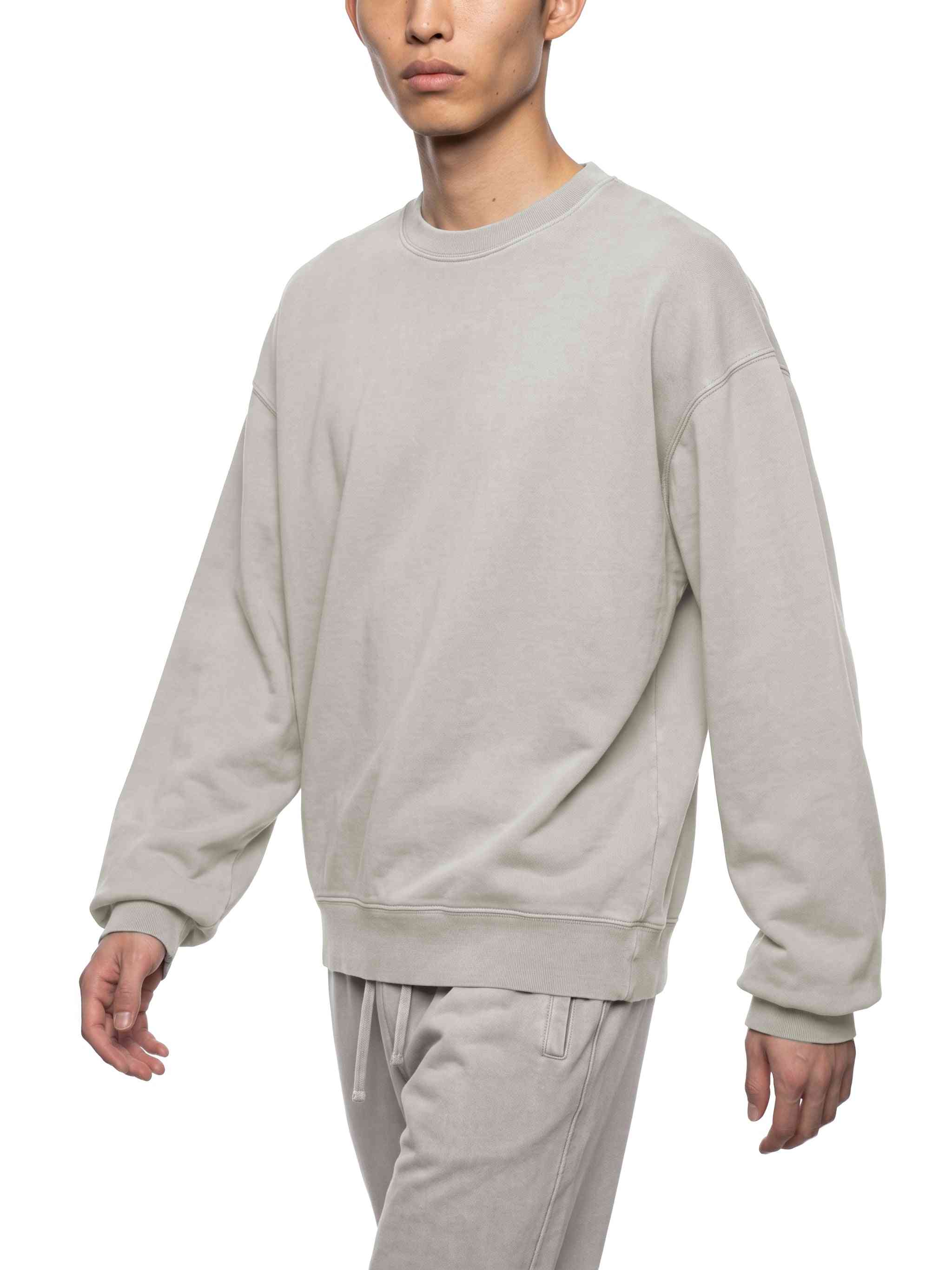 A man wearing a light gray crewneck sweatshirt and matching gray sweatpants, shown from the chin down against a plain white background.
